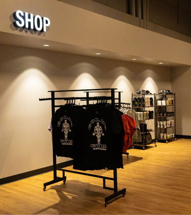 Gold’s Gym Arvada Pro Shop with branded apparel and training essentials displayed under shop lighting.