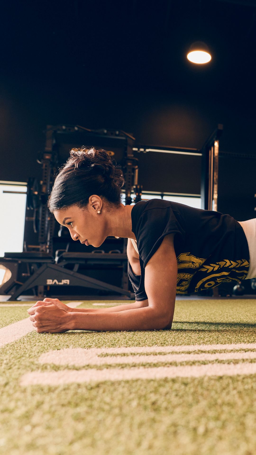 Gold's Gym Greeley member performing a forearm plank on the indoor turf training area