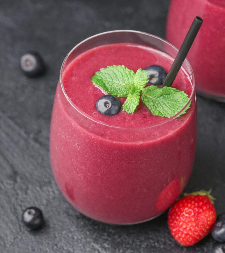 Close up of a bright berry smoothie with blueberries, mint, and a straw used to feature the smoothie bar at Gold’s Gym Greeley