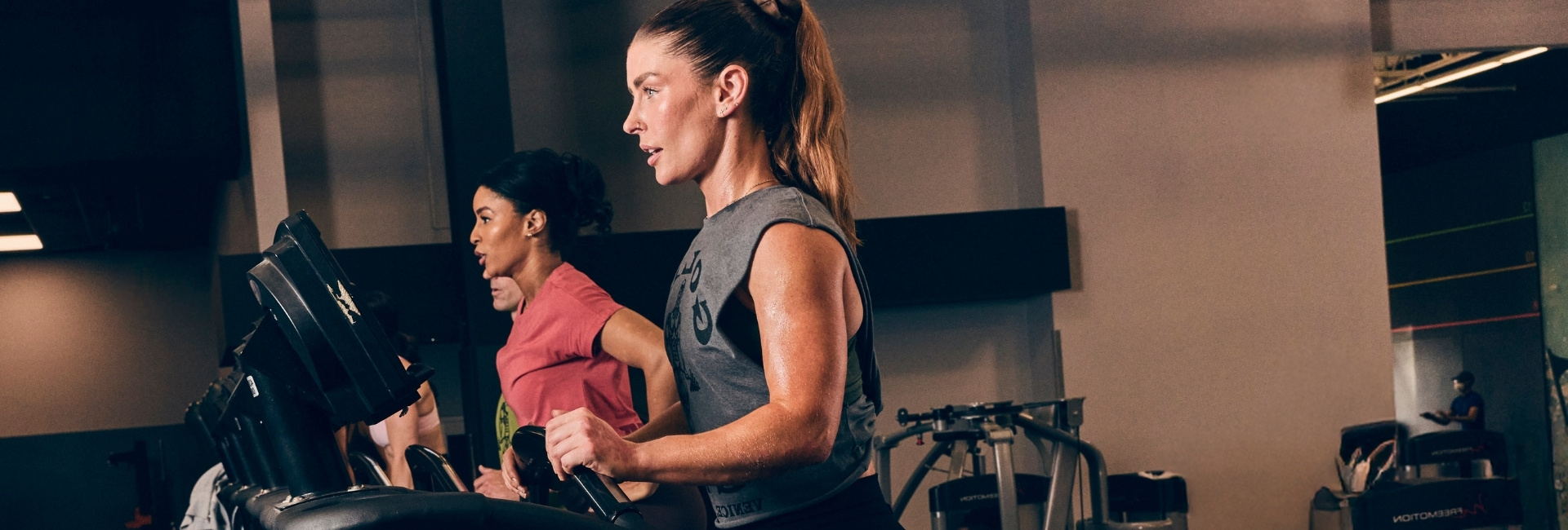 Two women training on stair climber machines at Gold’s Gym Greeley focused on intense cardio in a serious training environment