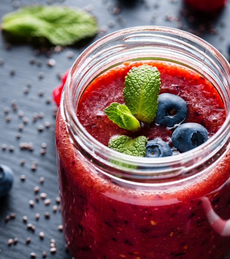 Close-up of a berry smoothie topped with blueberries and mint, representing the smoothie bar offerings at Gold’s Gym Longmont